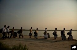 Indian election officials with polling materials walk to board a country boat to reach a polling center in a remote river island in the River Brahmaputra in Kamrup district, west of Gauhati, Assam, India, April 22, 2019.