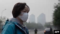 FILE - A woman wears protective mask to fight pollution in Beijing on Oct. 22, 2018. (Nicolas Asfouri/AFP)
