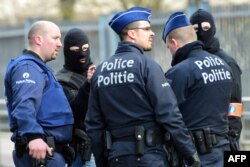 Policemen speak at a security perimeter near Maalbeek metro station, on March 22, 2016 in Brussels, after a blast at this station near the EU institutions caused deaths and injuries.