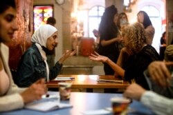 Seorang perempuan Palestina mengobrol dengan seorang perempuan Israel selama program pertukaran bahasa dengan model kencan kilat, di Yerusalem, 27 Oktober 2021. (Foto: REUTERS/Ronen Zvulun)