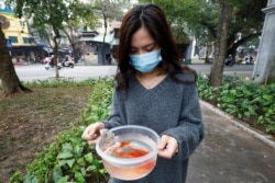 A woman prepares to release carps to Hoan Kiem lake on Kitchen God's Day as part of the traditional Vietnamese Lunar New Year celebrations, the biggest festival of the year in Hanoi, Vietnam February 4, 2021. REUTERS/Kham