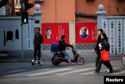 FILE - People cross a street in front of posters depicting late Chairman Mao Zedong (R) and China's President Xi Jinping in Shanghai, China, March 1, 2016.
