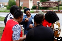 Members of Mount Olive Baptist Church pray near a municipal building that was the scene of a shooting, June 1, 2019, in Virginia Beach, Va