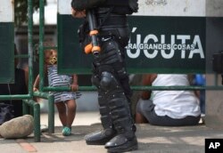 FILE - A Venezuelan child stands at a checkpoint near the Simon Bolivar International Bridge in La Parada, Colombia, Feb. 27, 2019, on the border with Venezuela whose government closed the bridge to block aid from entering.