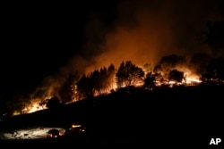 Firefighters watch from their fire trucks as wildfires continue to burn, Oct. 12, 2017, near Calistoga, California.