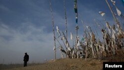 An ethnic Uighur stands in front of a grave at the cemetry surrounding the tomb of Imam Asim in the Taklamakan Desert outside the village of Jiya near Hotan, Xinjiang Uighur Autonomous Region, China, March 21, 2017.