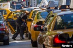 FILE - A woman exits a taxi on Third Avenue in heavy traffic. Carpooling can help reduce one's carbon footprint.