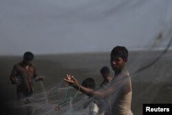 FILE - Rohingya refugees shake out fish from nets after the days catch on Shamlapur beach in Cox's Bazar, Bangladesh, March 21, 2018.