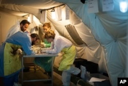 FILE - Cristina Cattaneo, right, and her team collect post-mortem data from shipwreck victims to obtain information for a future identification at the NATO base in the Sicilian town of Melilli, Italy, Oct. 8, 2016.