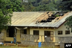 FILE - A woman stands outside a damaged school's dormitory, after it was set on fire, in Bafut, in the northwest English-speaking region of Cameroon, Nov. 15, 2017.