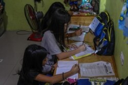 Siswa memulai tahun ajaran baru dengan pembelajaran daring, menggunakan ponsel dengan panduan modul pembelajaran yang telah dicetak, dari rumah mereka di pinggiran kota kota Mandaluyong Manila, 5 Oktober 2020. (Foto oleh Maria Tan / AFP)