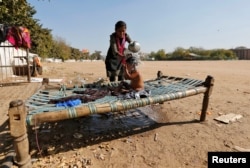 A woman gives a bath to a child on a cot, on the outskirts of Ahmedabad, India, Feb. 1, 2017.