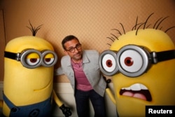 Actor Steve Carell poses with two life-size minion characters.