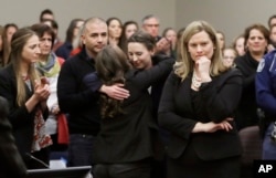 Former gymnast Rachael Denhollander, center, is hugged after giving her victim impact statement during the seventh day of Larry Nassar's sentencing hearing Wednesday, Jan. 24, 2018, in Lansing, Michigan.