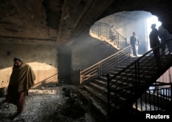 Afghan men inspect a burnt and damaged building at the site of yesterdayÕs blast and gunfire in Jalalabad, Afghanistan January 25, 2018.
