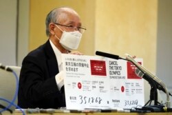 Pengacara Kenji Utsunomiya, perwakilan dari kelompok anti-Olimpiade, memegang papan yang menunjukkan sosok petisi online saat konferensi pers setelah mengajukan petisi kepada pemerintah Tokyo yang menyerukan pembatalan Olimpiade dan Paralimpiade Tokyo 2020. (AP Photo/Eugene Hoshiko)