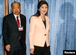 Thailand's PM Yingluck Shinawatra (R) and Deputy PM Surapong Tovichakchaikul arrive before a meeting with the Election Commission at the Royal Thai Air Force Academy in Bangkok, Apr. 30, 2014.