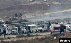 Forces loyal to Syria's President Bashar al-Assad sit on a tank as a convoy of buses and other vehicles bringing people out of eastern Aleppo turns back in the direction of the besieged rebel enclave, Syria, Dec. 16, 2016.