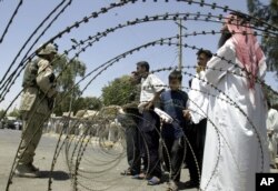 FILE - Iraqis try to persuade a U.S. soldier to enter the central bank in the northern city of Mosul during a protest, July 27, 2003.