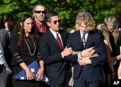 Parents of Riley Howell, Natalie Henry-Howell, center left, stands next to Thomas Howell, comforting their son Teddy, after a memorial service for Riley Howell in Lake Junaluska, N.C., May 5, 2019.
