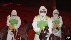 Workers wearing protective gears, spray antiseptic solution as a precaution against the spread of MERS, Middle East Respiratory Syndrome, virus at the Sejong Culture Center in Seoul, South Korea, Tuesday, June 16, 2015.