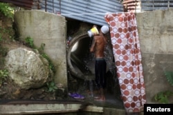 Israel Ayala takes a bath with water coming through a pipe, after the island was hit by Hurricane Maria in September, in Toa Alta, Puerto Rico, Oct. 19, 2017.