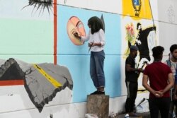 In this Sunday, Nov. 17, 2019 photo, an Iraqi artist woman draws graffiti at the Saadoun Tunnel, in Baghdad, Iraq. The tunnel that passes under Baghdad’s landmark Tahrir Square has become an ad hoc museum for Iraq's revolution: Young artists draw images a