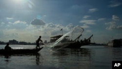 A fisherman casts his fishing net next to a ferry in the Mekong river near Phnom Penh, Cambodia, Tuesday, Dec. 1, 2015.