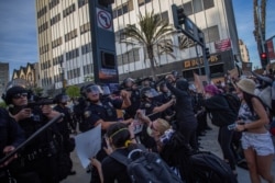 Demonstrators try to block Police officers while they take position aiming towards the crowd