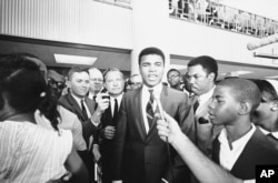FILE - With one of his attorneys Quinnan Hodges (L) of Houston, looking on, Muhammad Ali speaks to the press, radio and television after an all-white jury found him guilty of refusing to be inducted.