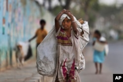 A girl collecting reusables walks in Hyderabad, India, March 9, 2016. Child labor remains widespread in India, where an estimated 13 million children work, with laws meant to keep kids in school and out of the workplace routinely flouted.