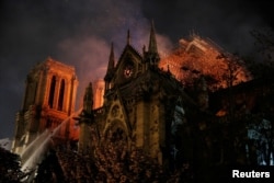 Sparks fill the air as Paris Fire brigade members spray water to extinguish flames as the Notre Dame Cathedral burns in Paris, April 15, 2019.