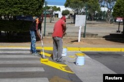 Workers paint a pedestrian crossing on a street in Porlamar, Venezuela, Sept. 12, 2016.