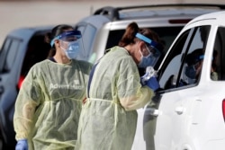 Healthcare workers conducts COVID-19 tests at a drive-thru coronavirus testing site, Tuesday, April 21, 2020, in Sanford, Fla. (AP Photo/John Raoux)