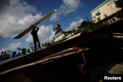 Carlos Ventura carries a corrugated metal sheet to be used for a ceiling, while he helps a neighbour to rebuild her house, which was partially destroyed by Hurricane Maria.