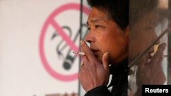 A man smokes in front of a no smoking sign in Shanghai, Jan. 10, 2014.