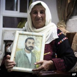 Zahra Falana sits at her home with a picture of her son, Ata Falana, who was relocated to Gaza after being released October 18, 2011.