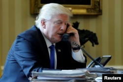 FILE - President Donald Trump conducts a phone call in the Oval Office at the White House in Washington, Jan. 28, 2017.