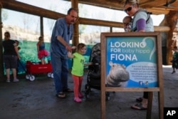 In this Wednesday, April 12, 2017, photo, visitors read a sign depicting Fiona, the Cincinnati Zoo & Botanical Gardens' new baby hippopotamus, as they pass through the Hippo Cove exhibit.