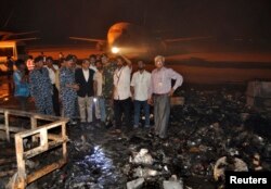 FILE - The governor of Sindh province, Ishrat ul Ebad, and security officials visit a damaged area after an attack on Jinnah International Airport in Karachi, Pakistan, June 9, 2014.