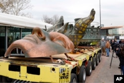 The original torch of the Statue of Liberty and a replica of her face rest on a hydraulically stabilized transporter, Nov. 15, 2018 in New York. The torch, which was removed in 1984 and replaced by a replica, was being moved into what will become its permanent home at a new museum on Liberty Island.