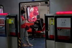 Commuters wearing face masks to help curb the spread of the coronavirus browse their smartphones inside a subway train in Beijing Wednesday, Feb. 10, 2021.