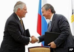 FILE - Igor Sechin, CEO of state-controlled Russian oil company Rosneft (right) and Exxon Mobil Corp. CEO Rex Tillerson shake hands after signing an agreement at the Black Sea port of Tuapse, southern Russia, June 15, 2012.