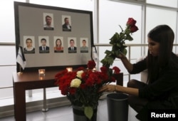 A woman places flowers in front of the portraits of crew members of the crashed Airbus A321 plane, operated by Russian airline Kogalymavia, in the company's office in Moscow, Russia, Nov. 2, 2015.