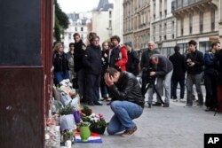 FILE - A man holds his head in his hands as he lays flowers in front of the Carillon cafe, in Paris, Nov. 14, 2015.
