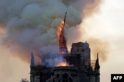 The steeple and spire of the landmark Notre-Dame Cathedral collapses as the cathedral is engulfed in flames in central Paris, April 15, 2019.