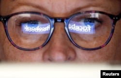 The Facebook logo is reflected on a woman's glasses in this photo illustration taken June 3, 2018