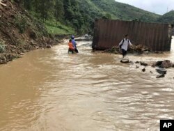 Residents wade through flood water in northern province of Son La, Vietnam Thursday Oct. 12, 2017.