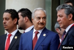 FILE - Khalifa Haftar (C), the military commander who dominates eastern Libya, leaves after an international conference on Libya in Paris, France, May 29, 2018.