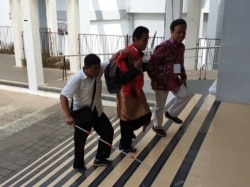 Wildan (tengah) dipandu Arif Maftuhin, Direktur Pusat Layanan Difabel UIN Sunan Kalijaga mengakses area yang belum diakrabinya di kampus. (Foto: VOA/ Nurhadi))